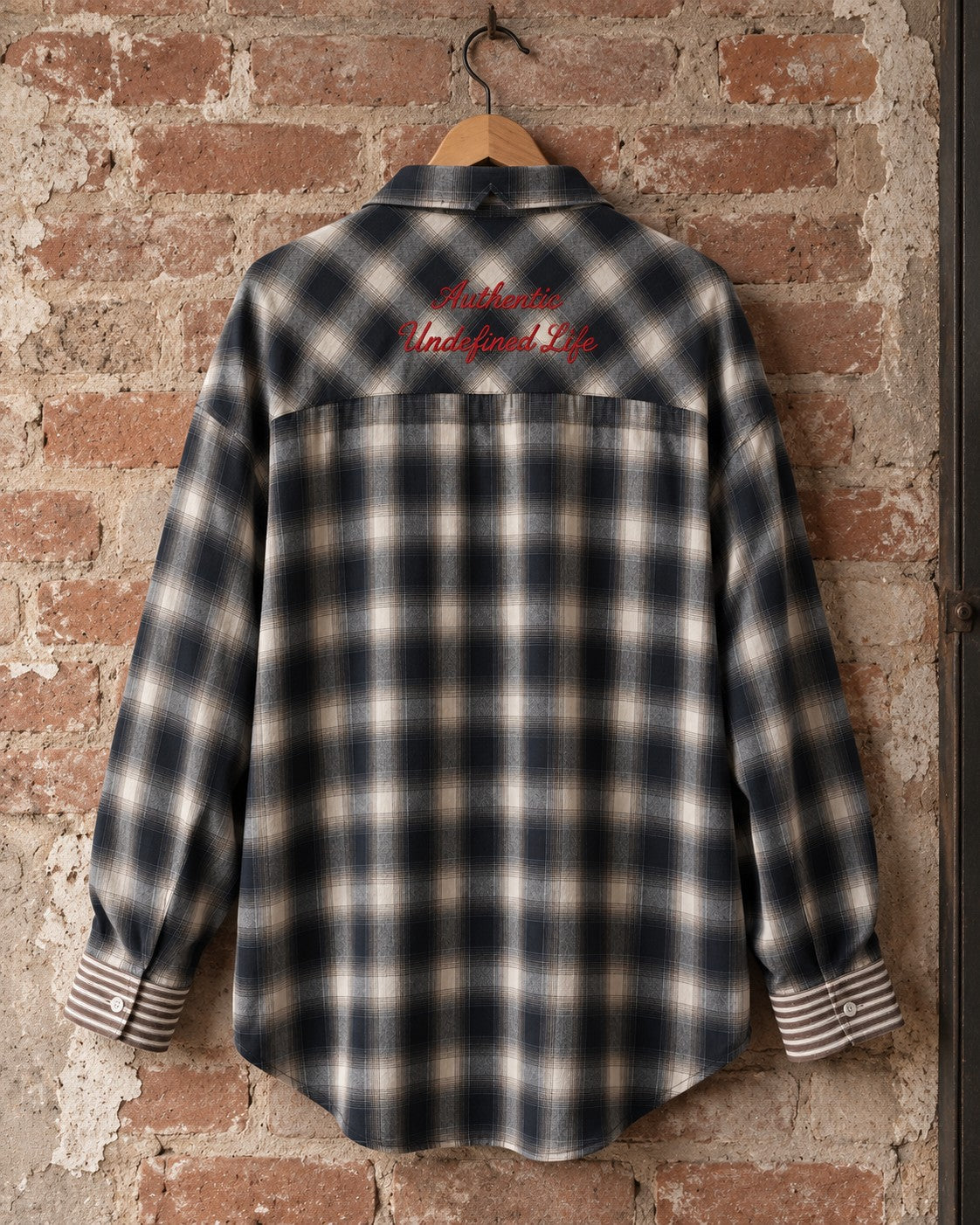 Camisa oversize de cuadro AÜL colgada en percha, espalda con bordado 'Authentic Undefined Life' en rojo