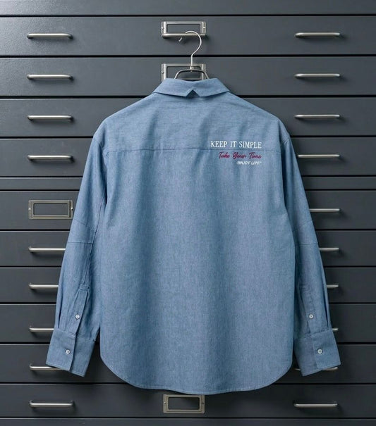 Camisa unisex oversize con tejido algodón efecto denim y contraste en interior cuello y puños con un tejido de rayas, fit relajado estilo minimalista y moderno y urbano. estampado en la espalda y en el bolsillo delantero una etiqueta con número de serie exclusivo y personalizado